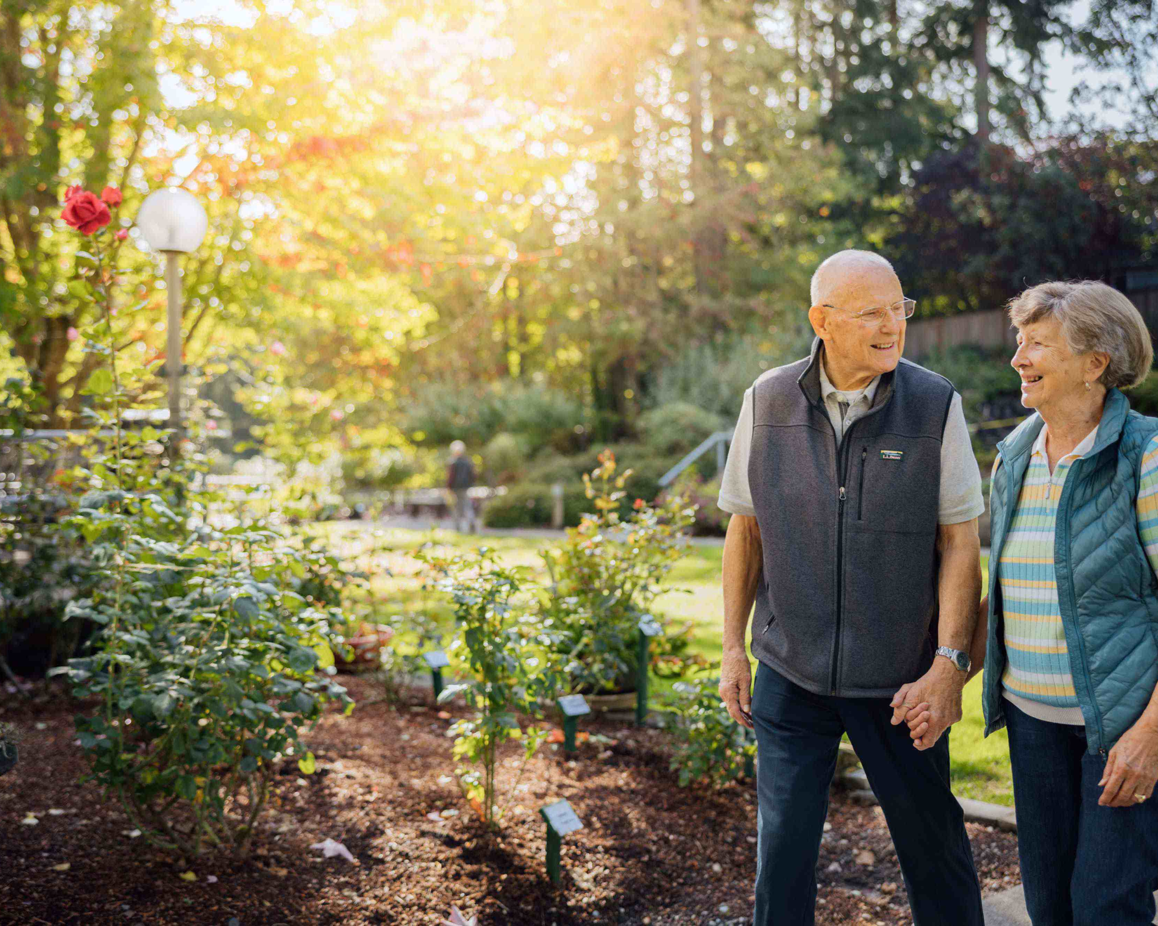 CRISTA Senior Living - Couple walks in sunlit garden on grounds at Cristwood Park in Shoreline.