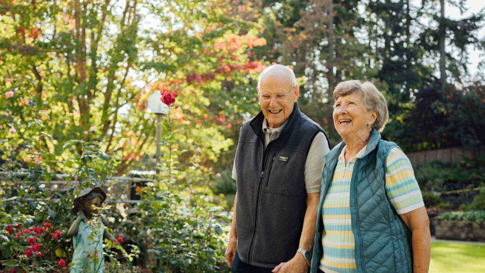 Couple walks in sunny garden at Cristwood Independent Living