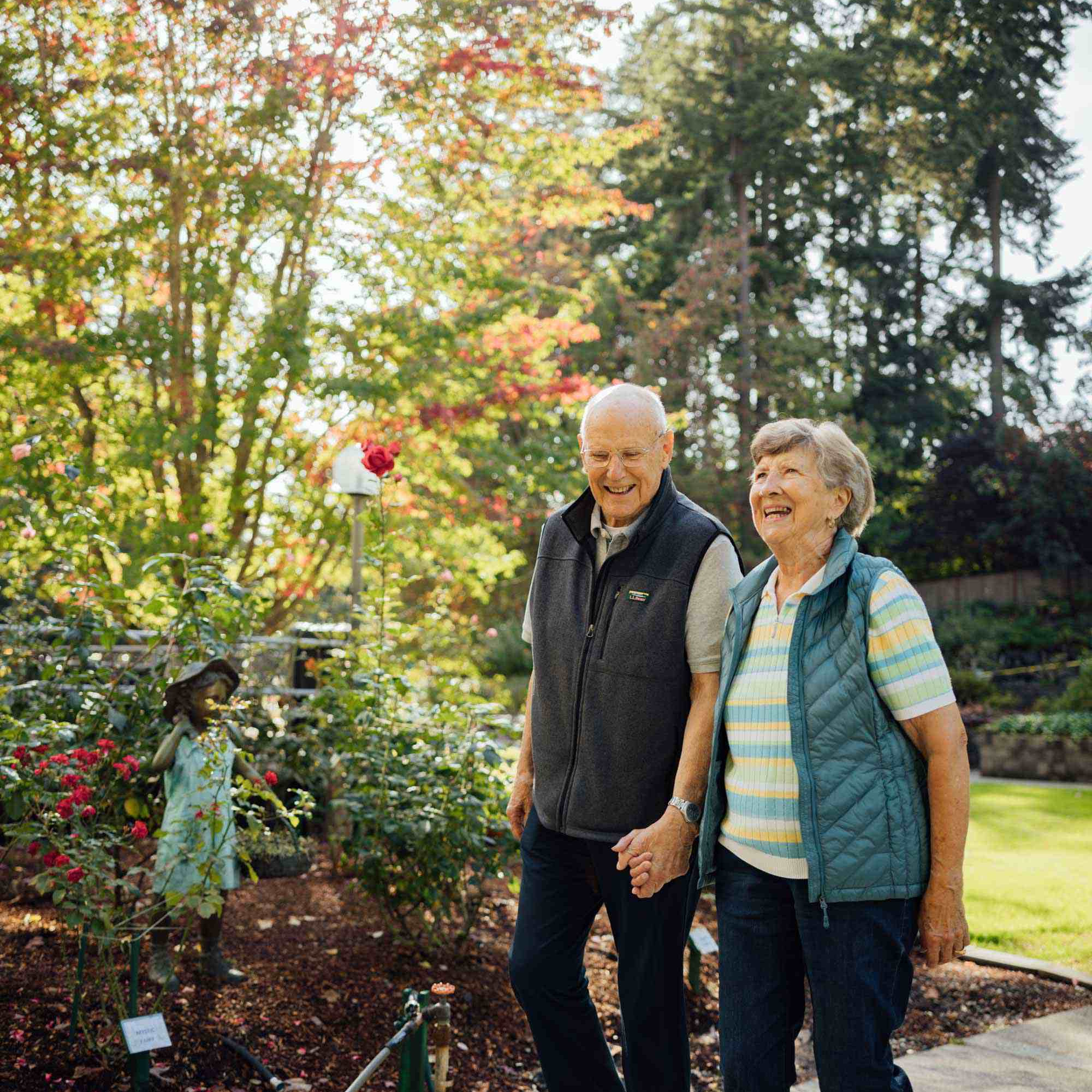 CRISTA Senior Living - Couple walks in sunny garden at Cristwood Independent Living